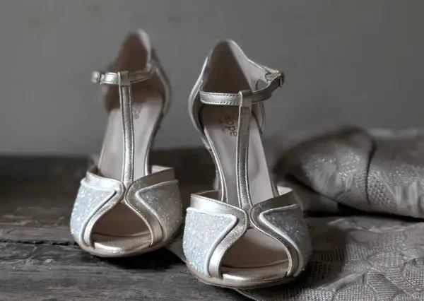 Scarpe dorate con glitter e cinturino a T, perfette da abbinare a un abito in pizzo per un look da cerimonia.