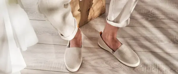 Un uomo indossa un outfit casual con espadrillas uomo in lino beige, pantaloni chiari e un dettaglio in tessuto bianco.