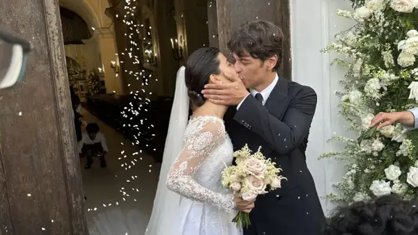 Alessandra Mastronardi e il suo sposo si baciano fuori dalla chiesa, tra petali di fiori e un'atmosfera di gioia per il loro matrimonio.