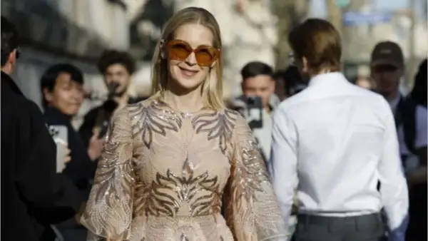 Donna con abito scintillante e occhiali da sole oversize, perfetta per un dress code cocktail donna.