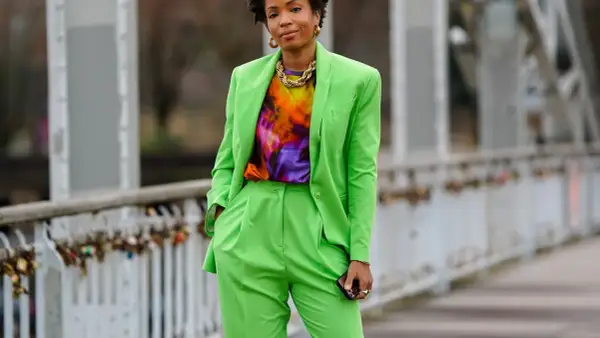 Donna con completo verde brillante, maglia tie-dye e collana dorata. Un look che celebra l'armocromia primavera con colori vivaci.