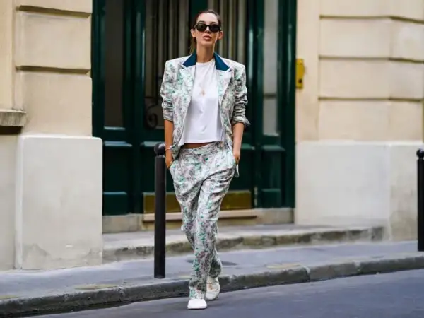 Un outfit da colloquio di lavoro senza tacchi: tailleur floreale con blazer e pantaloni ampi, t-shirt bianca e sneakers.