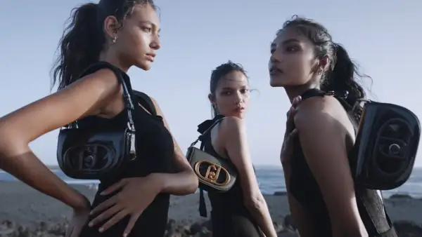 Tre modelle con borse Liu Jo, che marca è? Eleganti e moderne, posano sulla spiaggia con un look total black.